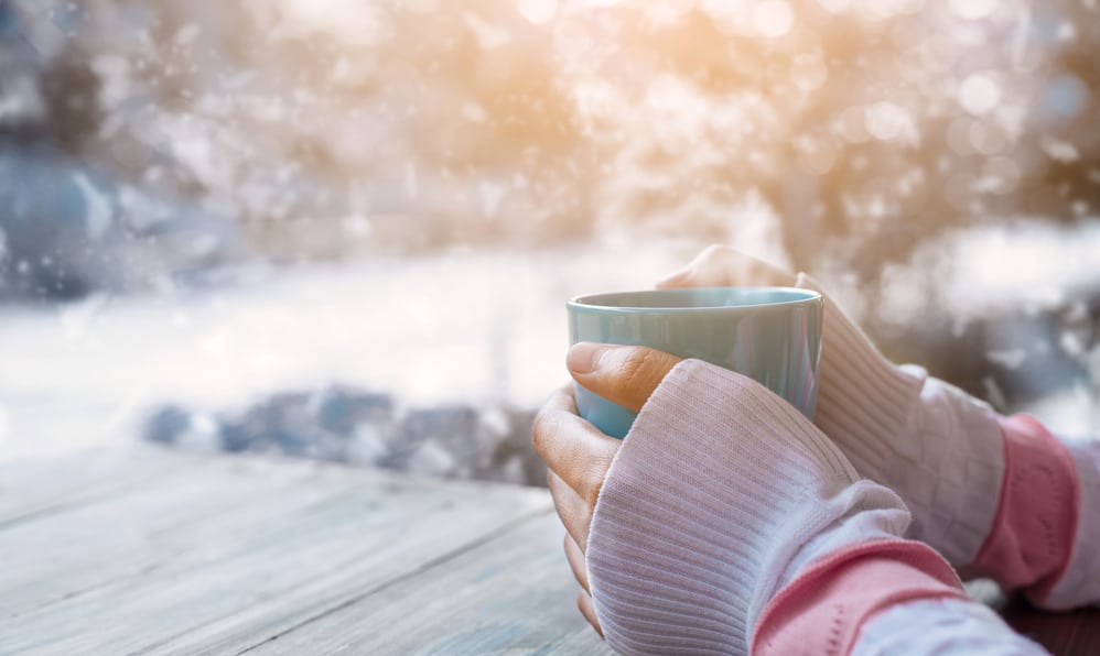 femme réchauffant ses mains froides autour d'une tasse de thé chaud